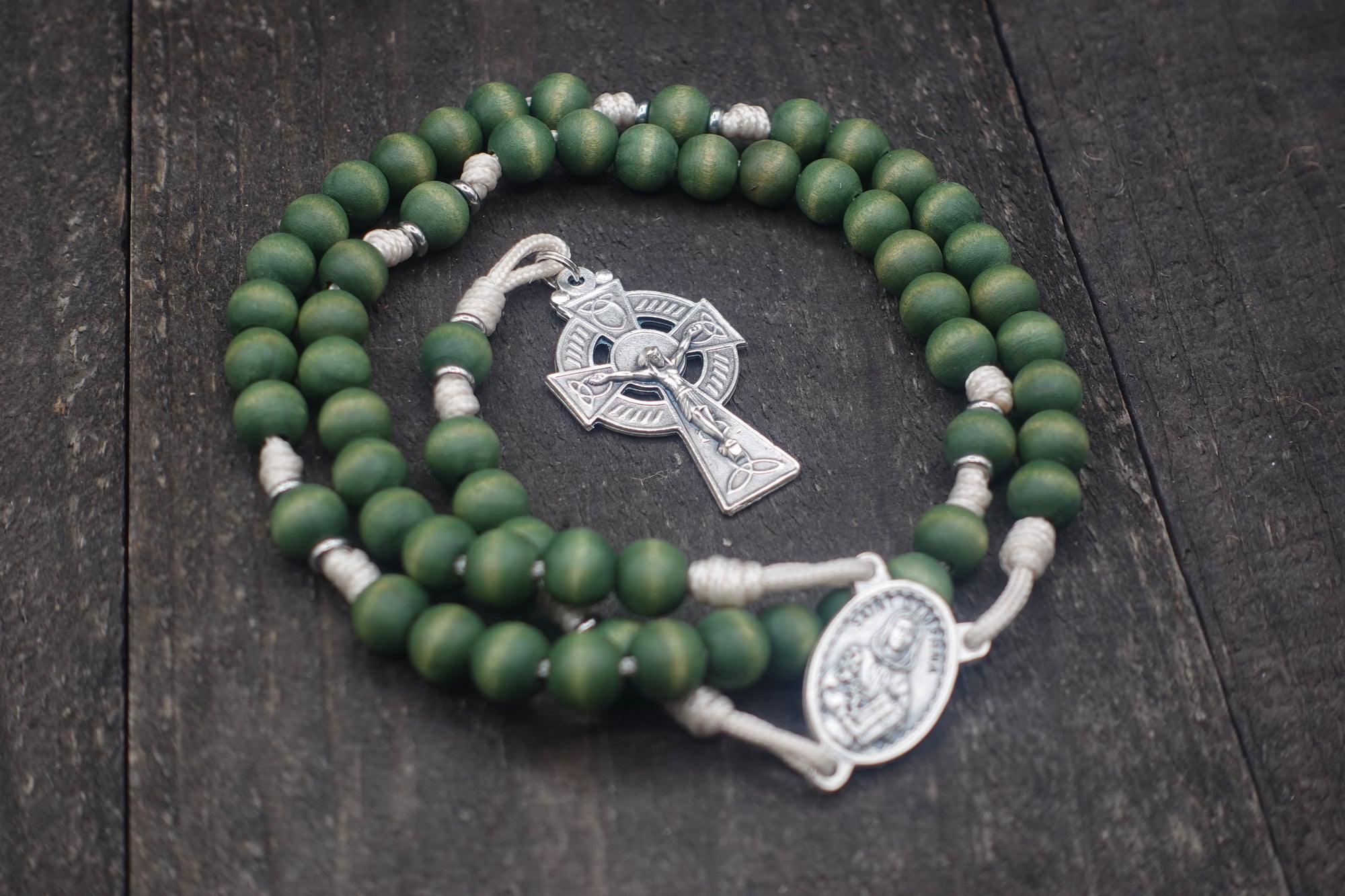 Close-up of silver Celtic crucifix on St. Dymphna rosary with forest green wooden beads