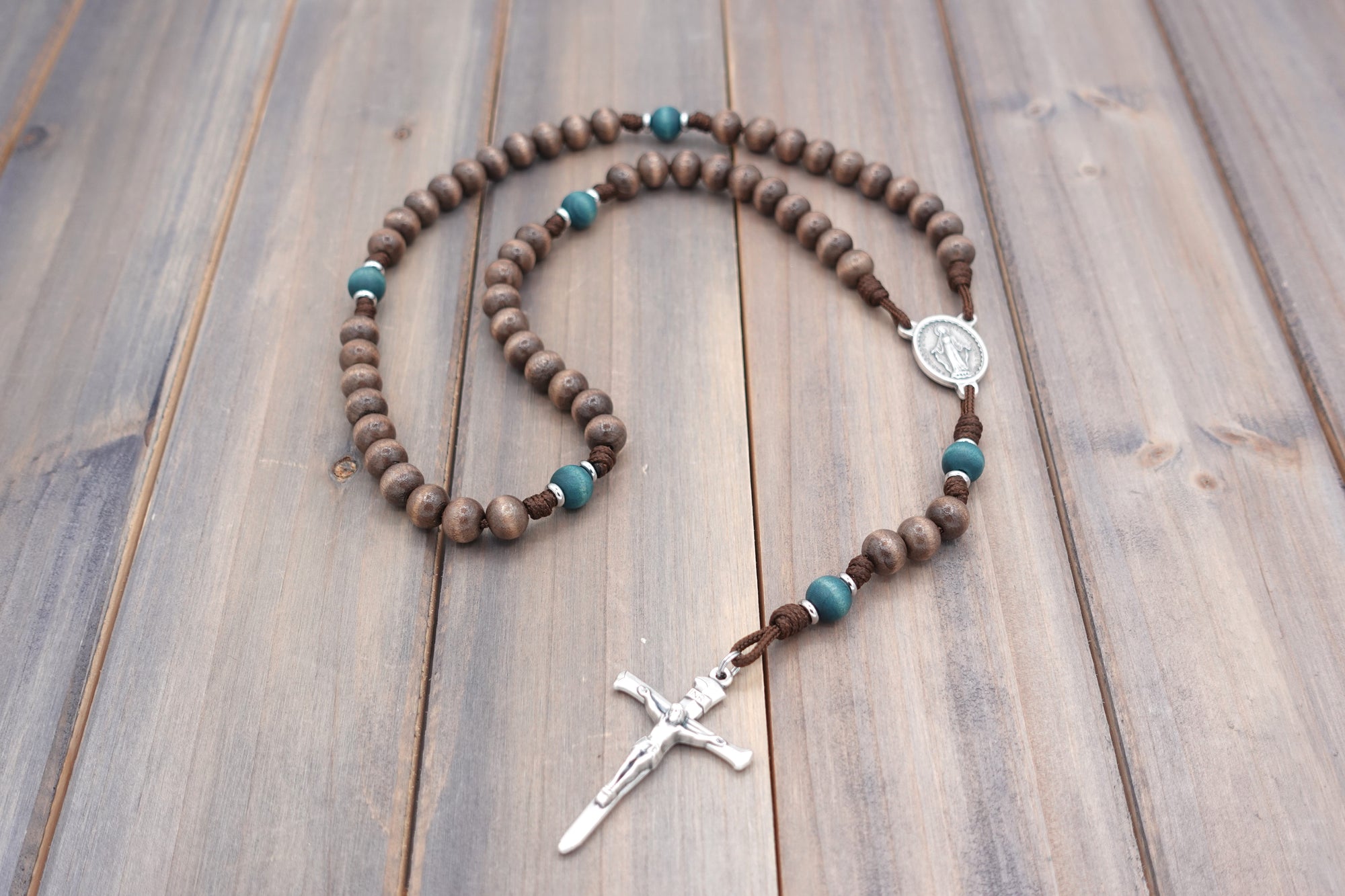 St. Kateri Tekakwitha rosary with gray-brown and teal wooden beads, silver Nails crucifix, and walnut paracord