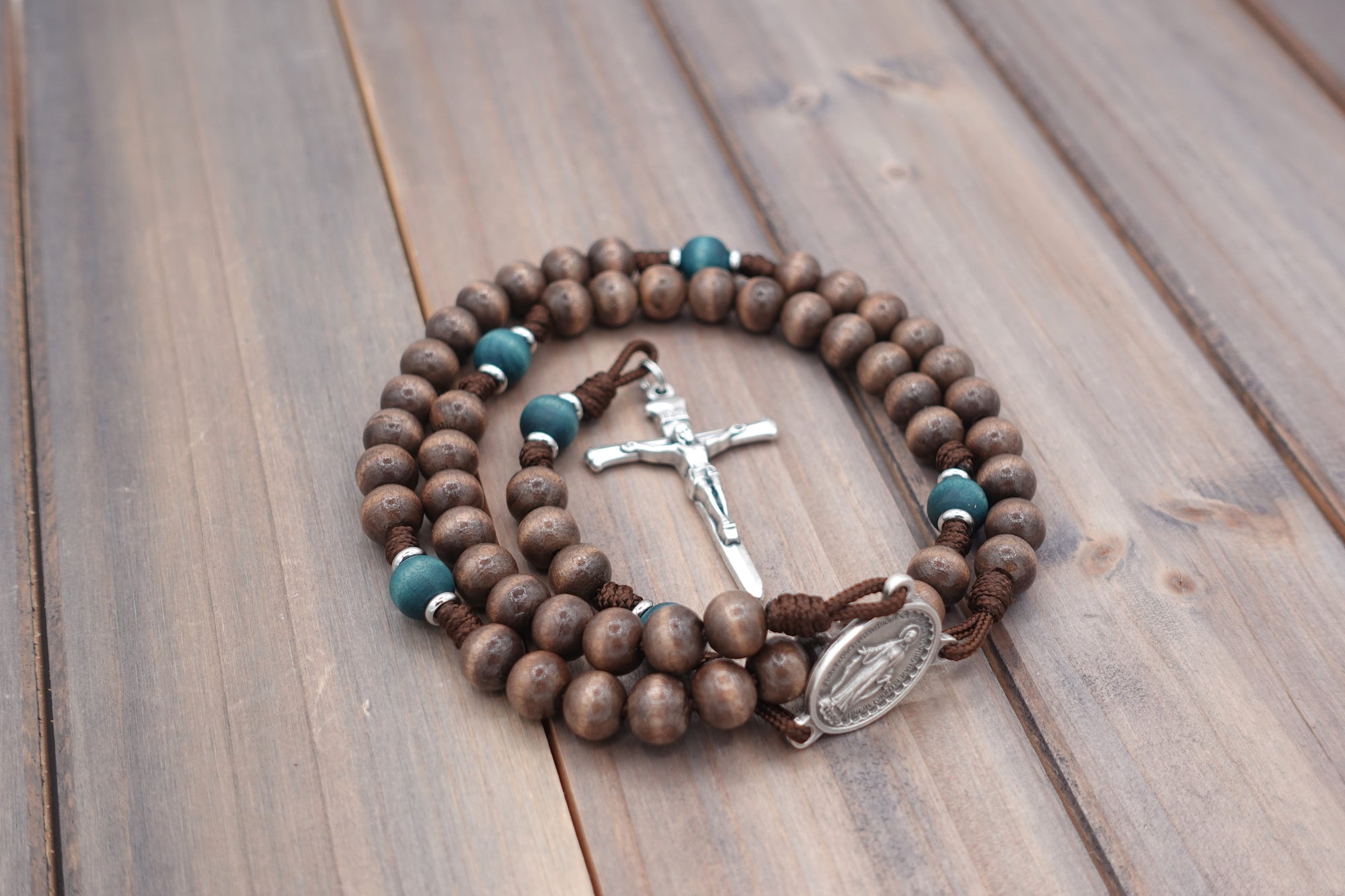 Handcrafted rosary featuring gray-brown Hail Mary beads, teal Our Father beads, and Miraculous Medal centerpiece