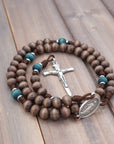 Handcrafted rosary featuring gray-brown Hail Mary beads, teal Our Father beads, and Miraculous Medal centerpiece