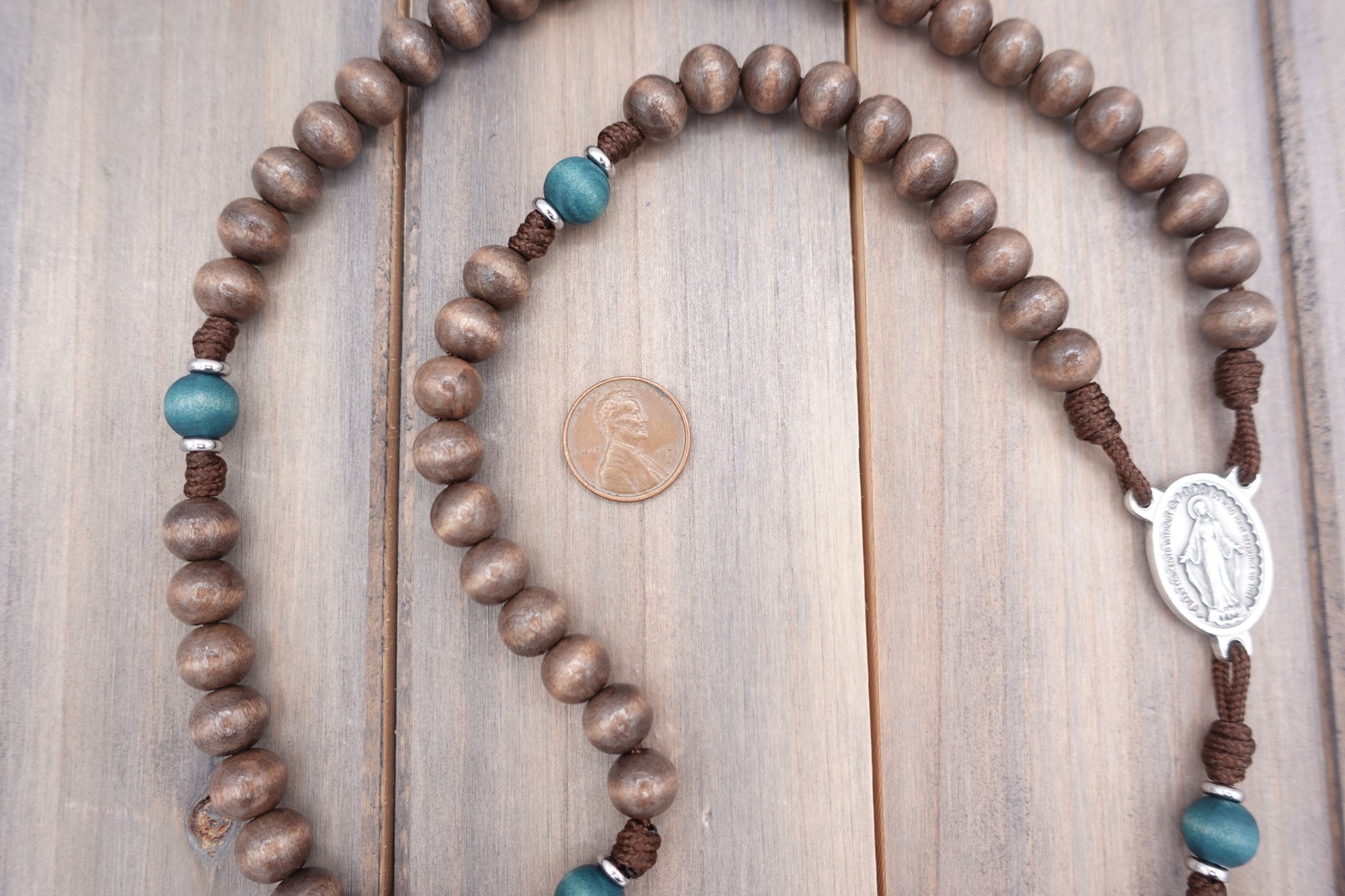 Close-up of gray-brown and teal wooden beads on St. Kateri Tekakwitha rosary showing heirloom craftsmanship