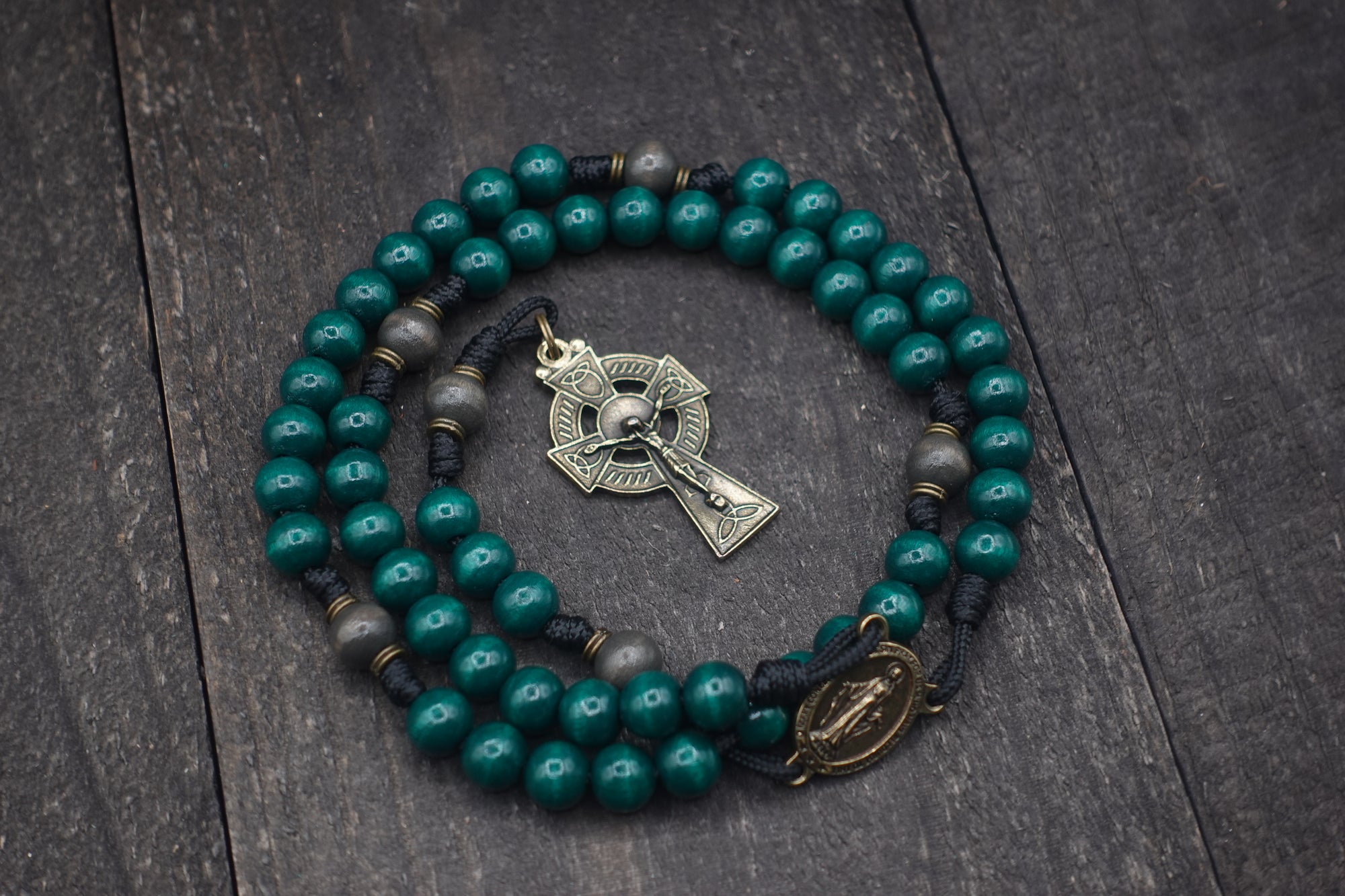 St. Patrick rosary with emerald green and charcoal wooden beads, bronze Celtic crucifix, and black paracord