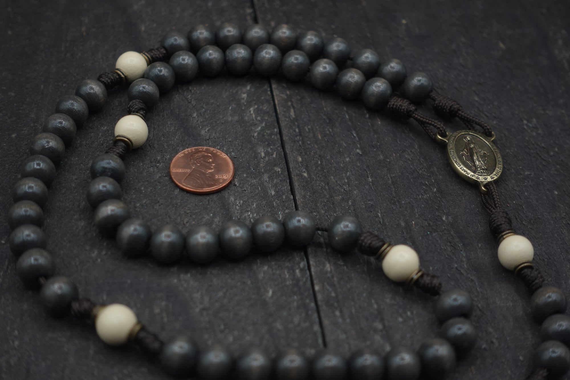 Close-up of bronze Pardon crucifix on Augustinian rosary with charcoal and white wooden beads