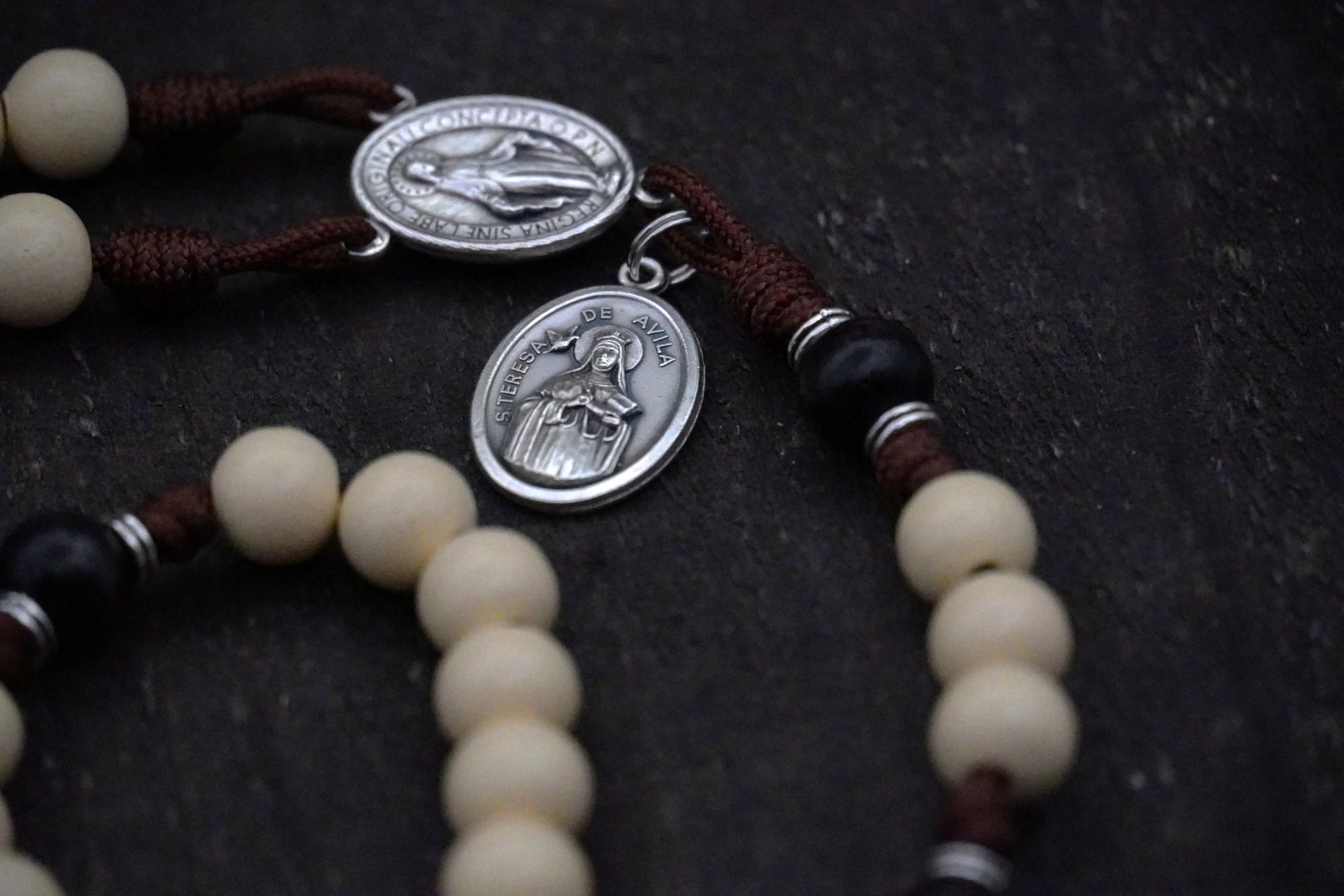 Close-up of vintage white and black wooden beads on St. Teresa of Ávila rosary showing heirloom craftsmanship