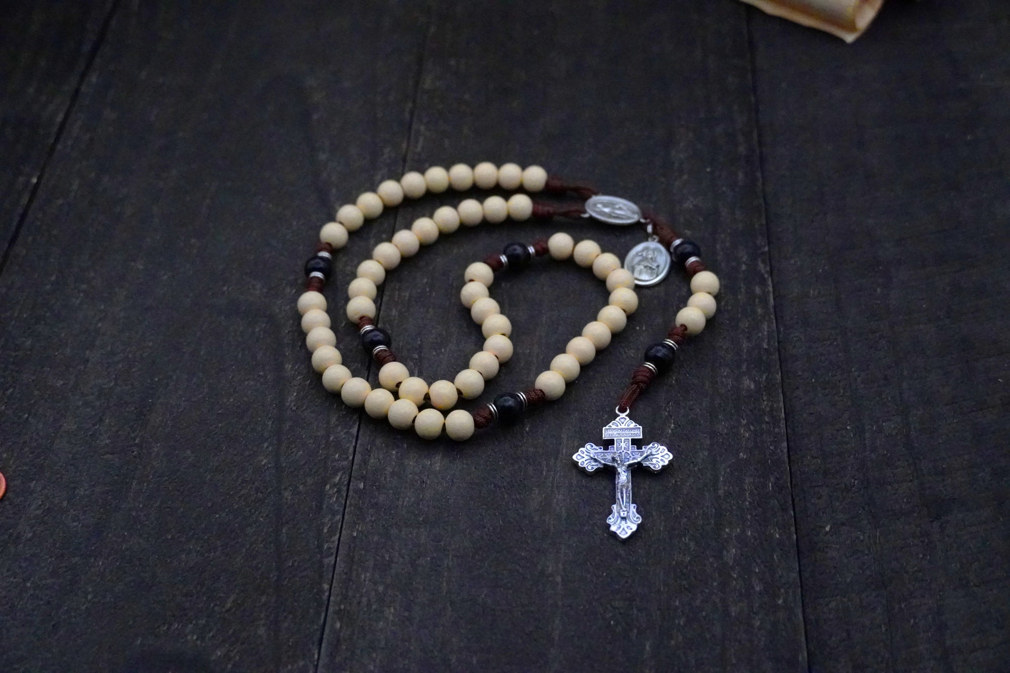 St. Teresa of Ávila rosary by Runewood Rosary combining vintage white and black wood beads, silver crucifix, and walnut paracord for faithful devotion