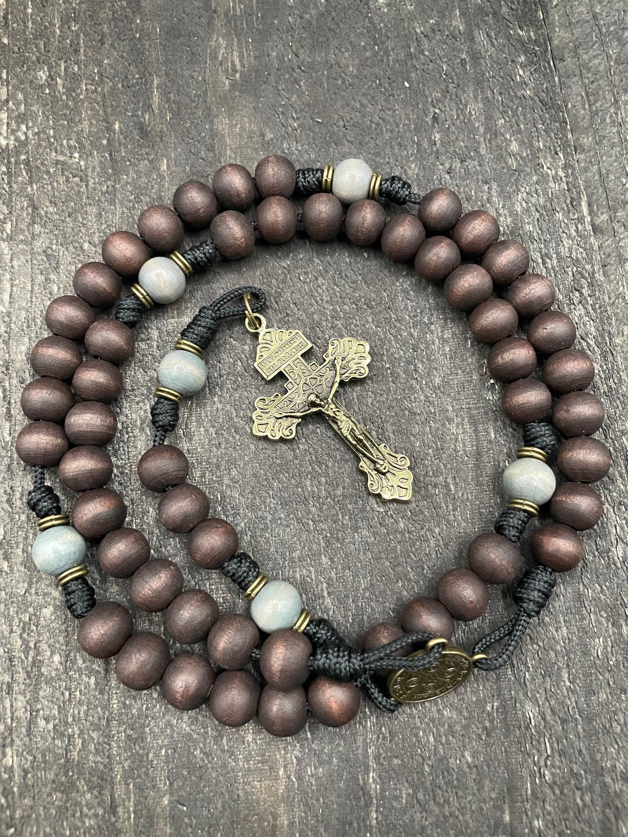 Handcrafted rosary with a traditional crucifix and beads resting on a wooden table, symbolizing faith and devotion