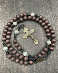 Handcrafted rosary with a traditional crucifix and beads resting on a wooden table, symbolizing faith and devotion