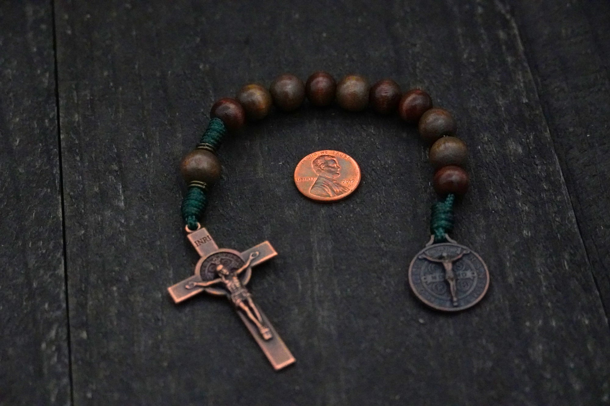 Handmade pocket rosary featuring gray-brown stained beads, copper crucifix, and emerald green paracord